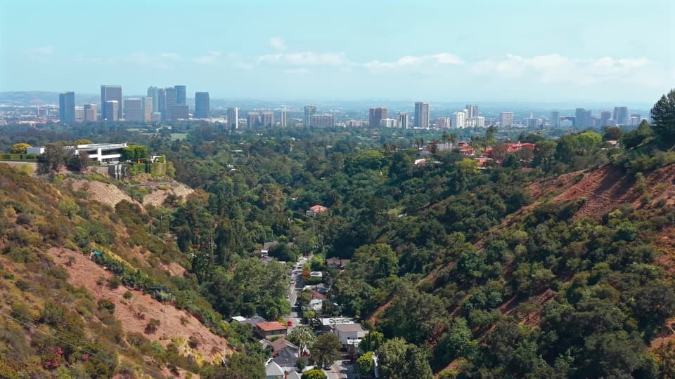 Aerial drone frame over the Bel Air hills toward the Century City skyline, the opening slide of the 947 N Beverly Glen Blvd carousel