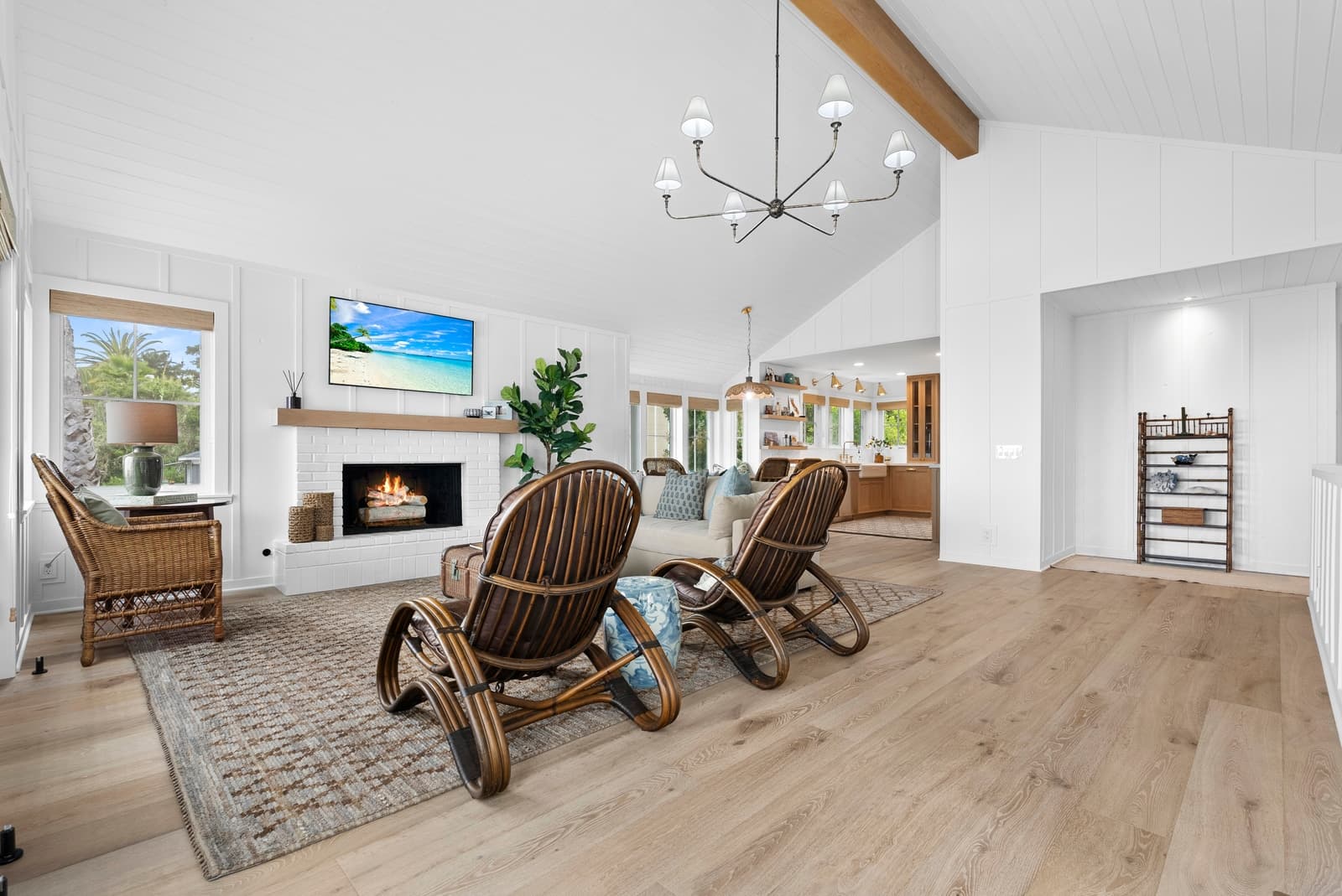 Farmhouse living room, rattan chairs, fire lit under a vaulted white ceiling