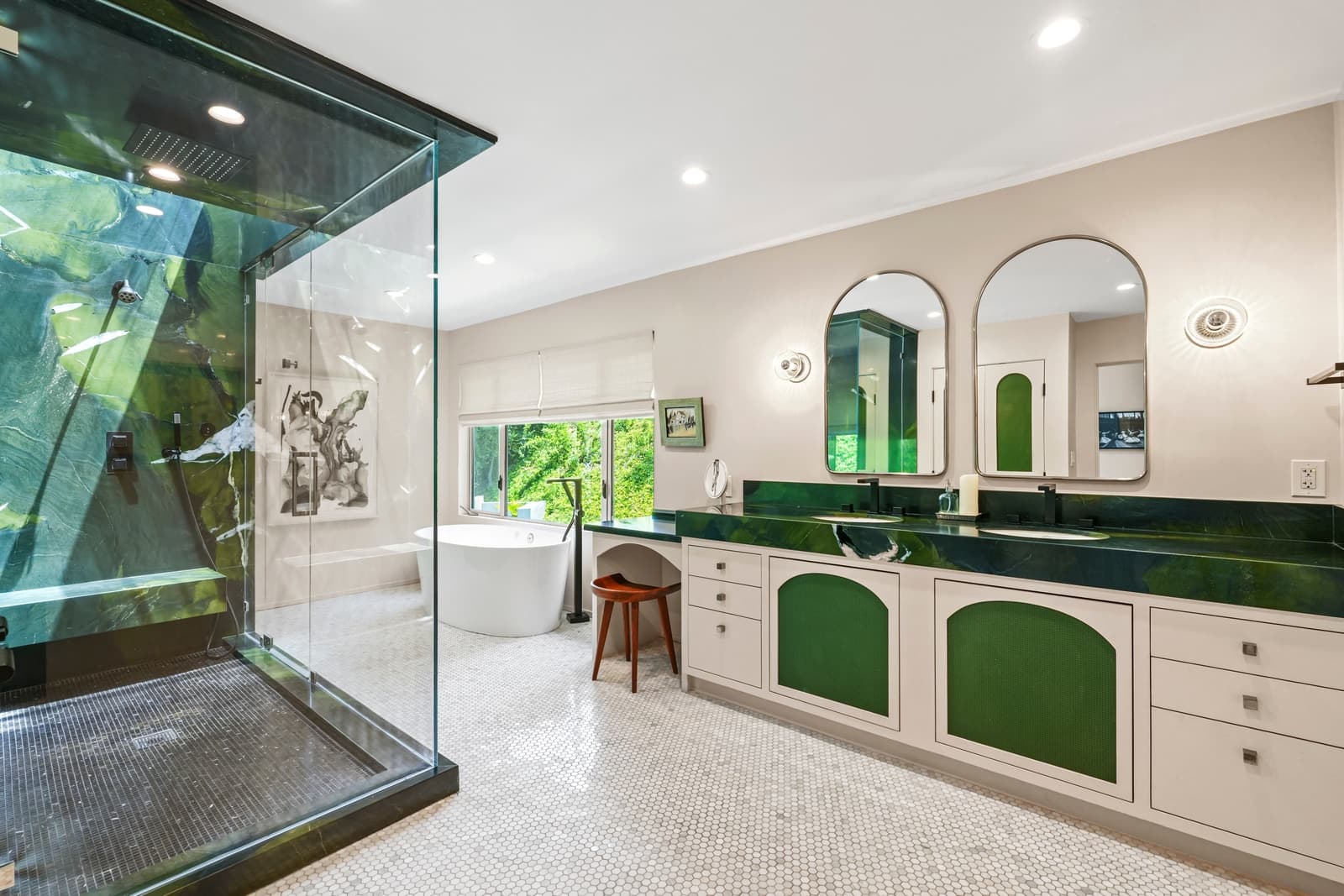 Green marble bath with a glass shower box and arched mirrors