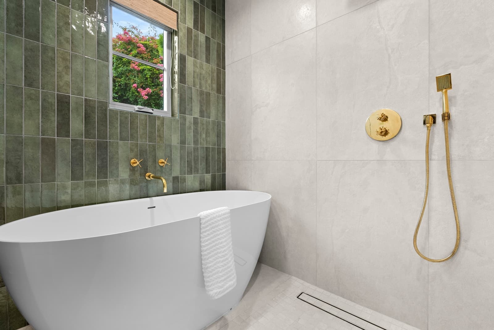 Green tile bath with a freestanding tub and brass fixtures
