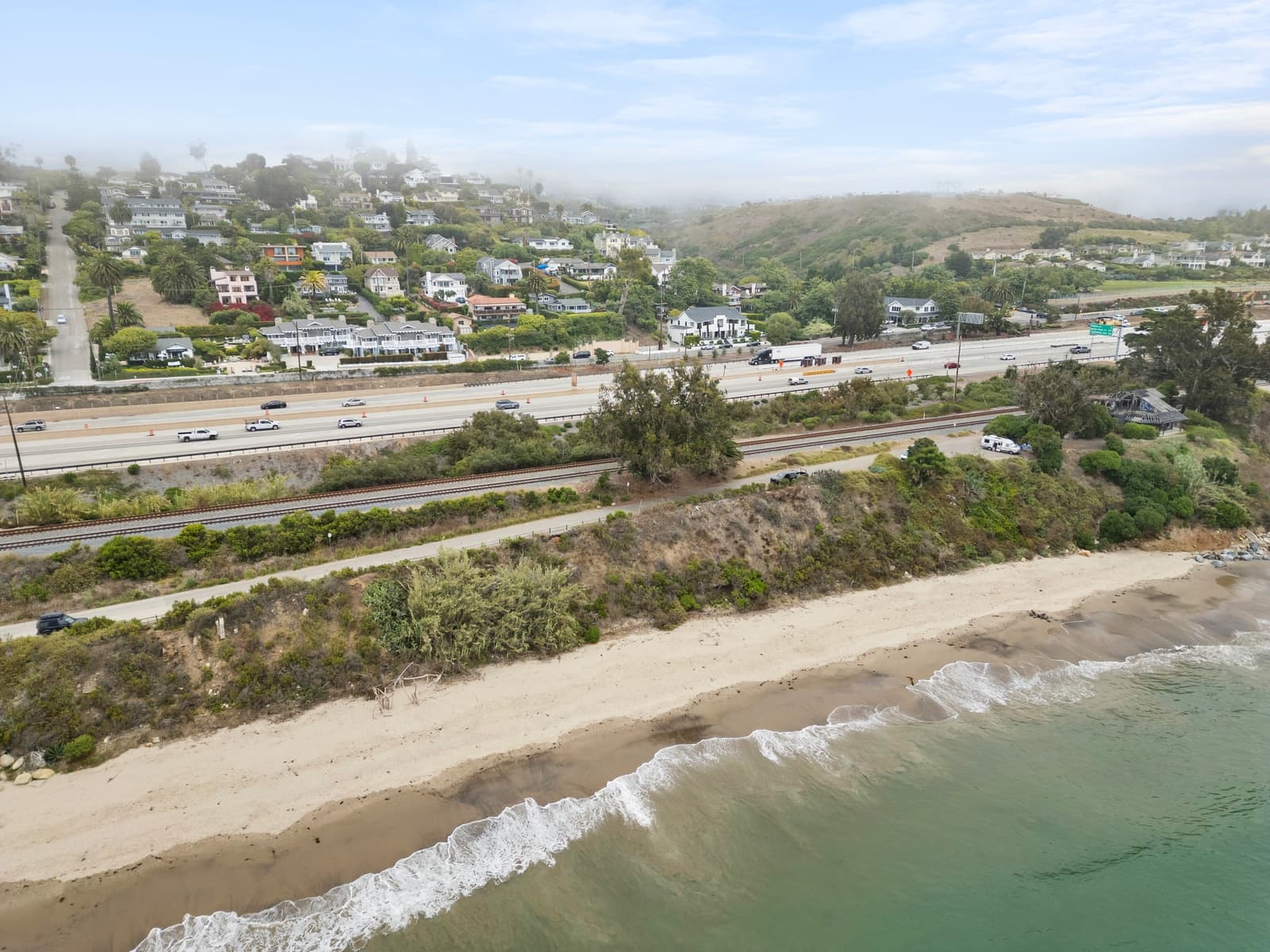 Drone over the Summerland coast, highway and beach below the bluff